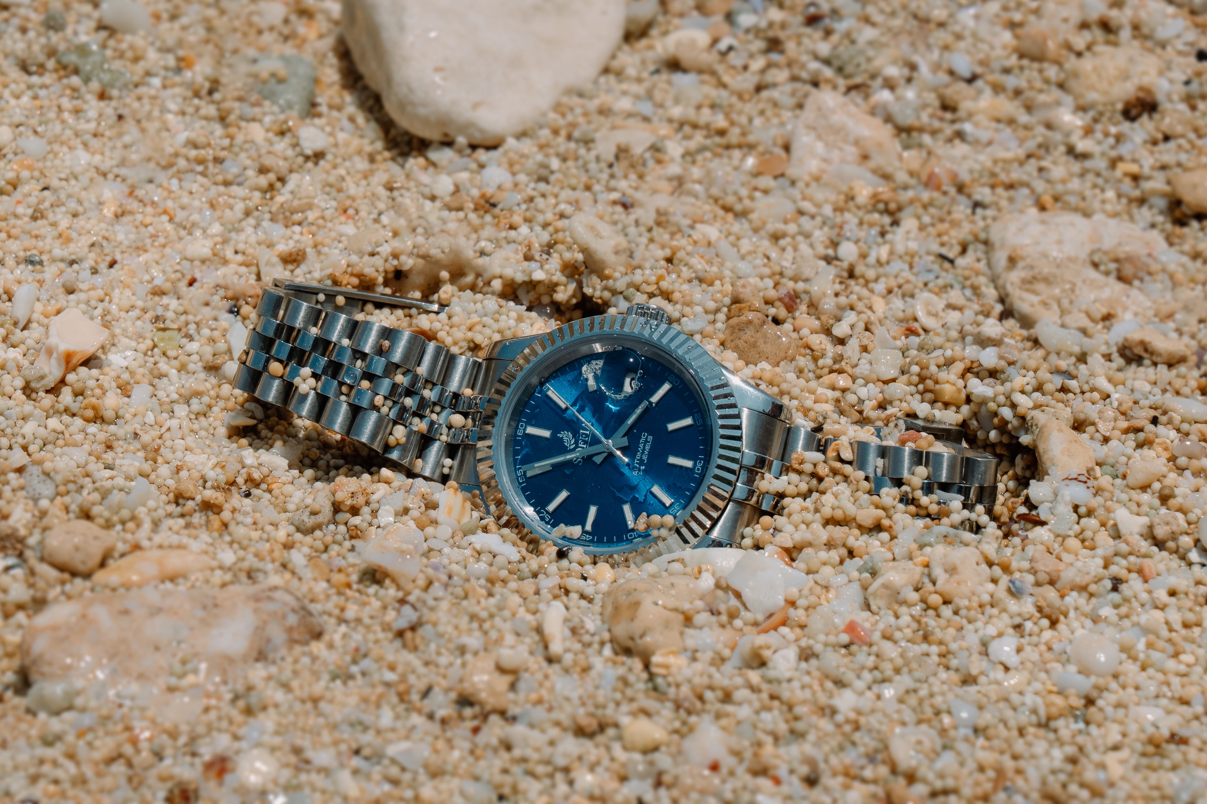 Beautiful blue navy dial watch layed down at the beach