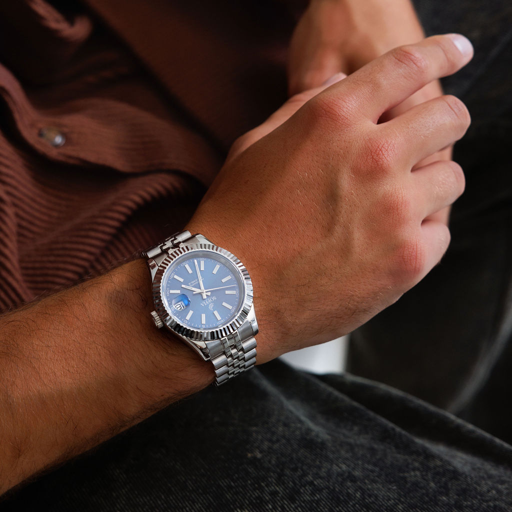 Close-up of a wrist wearing a silver watch with a blue face.