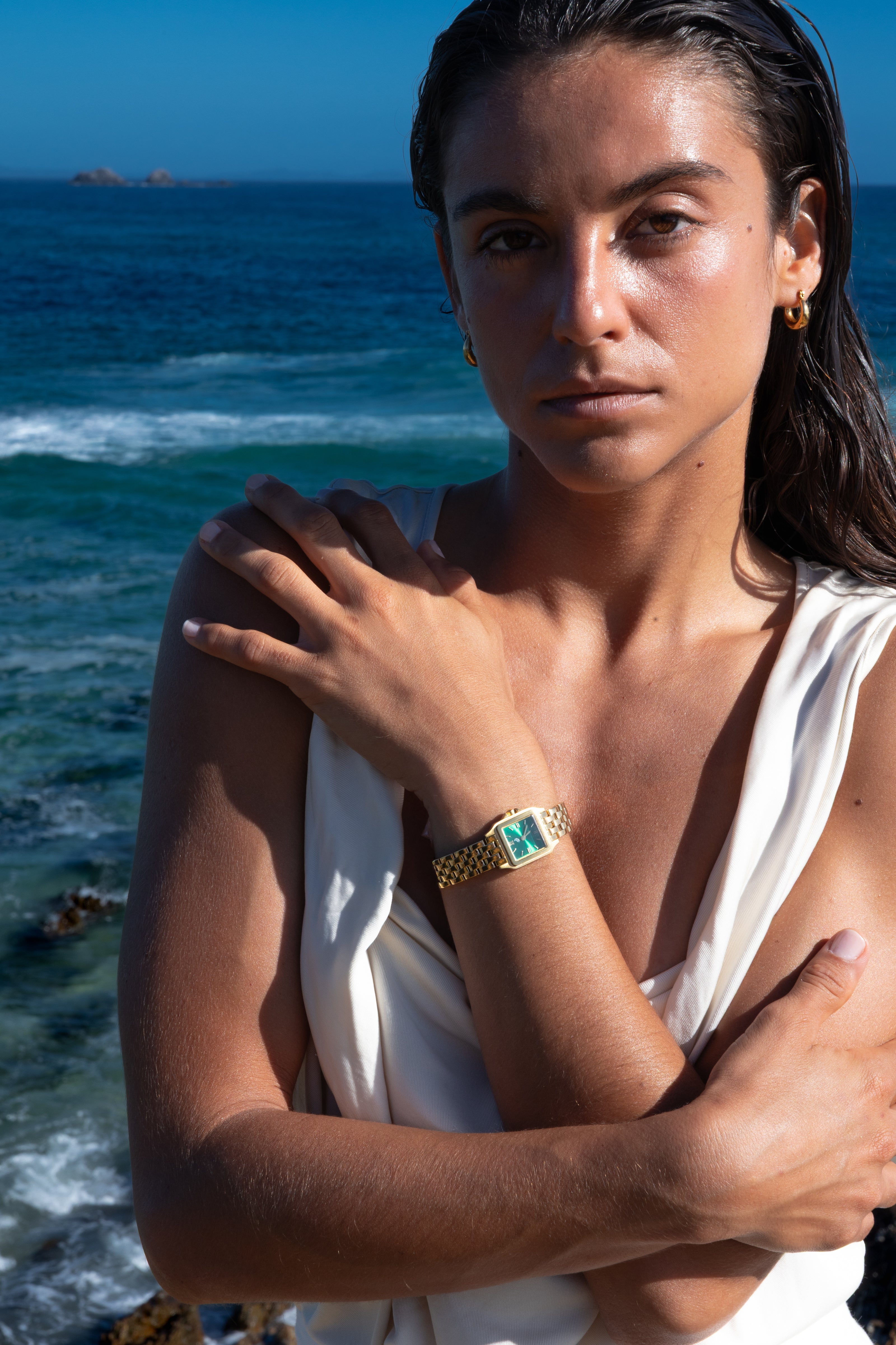Woman in a white dress standing by the ocean with waves in the background