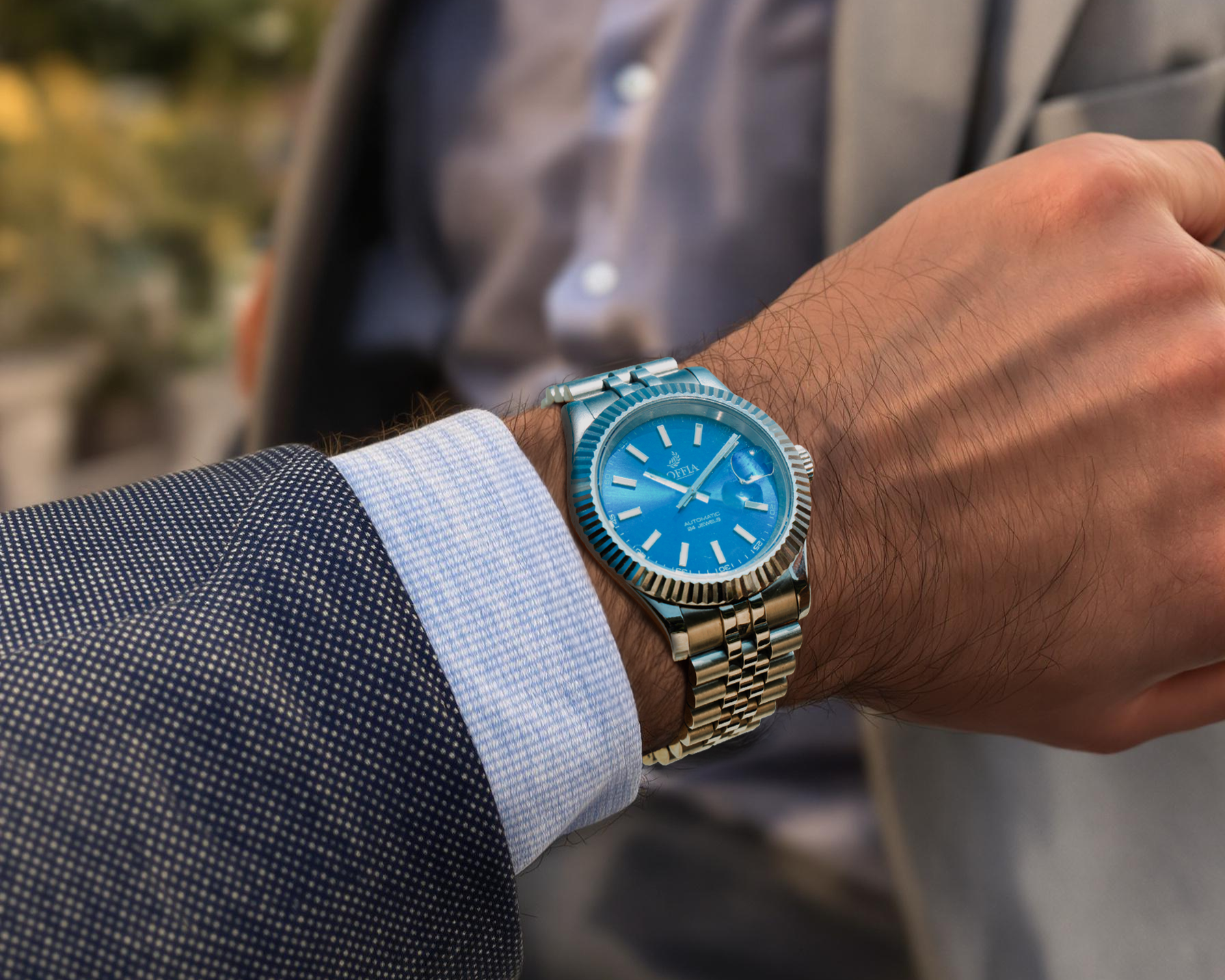 Close-up of a person wearing a watch with a blue face and stainless steel bracelet