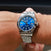 Silver watch with a blue face on a wrist against a dark background