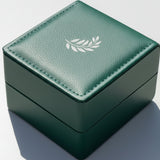 Green jewelry box with a leaf emblem on a light gray background