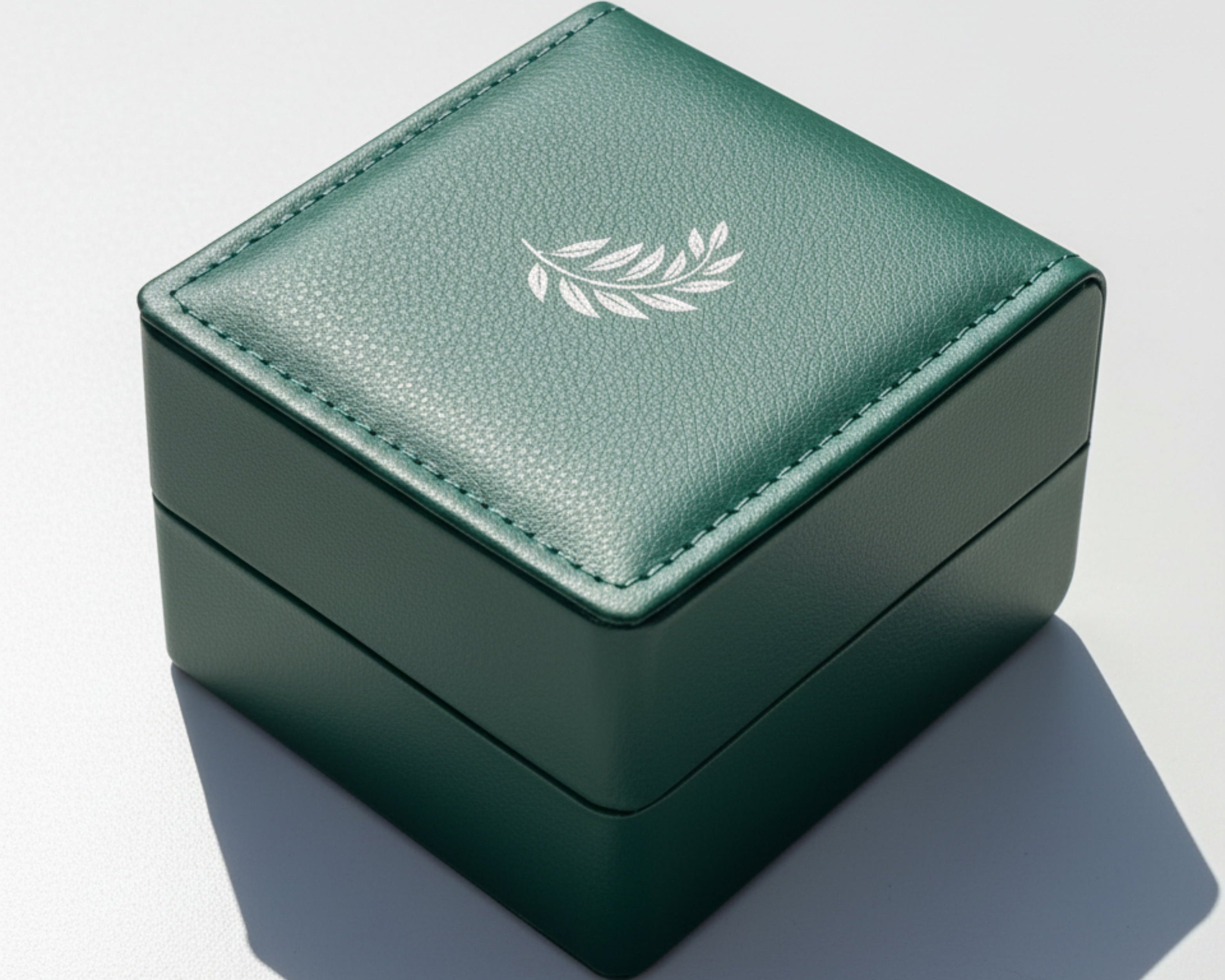 Green jewelry box with a leaf emblem on a light gray background